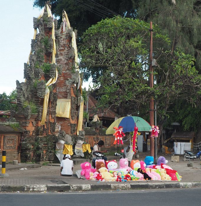 Colorful teddy bears for sale next to a shrine