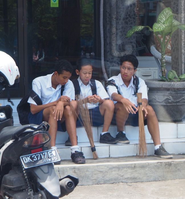 School boys have wisk brooms to clean the school