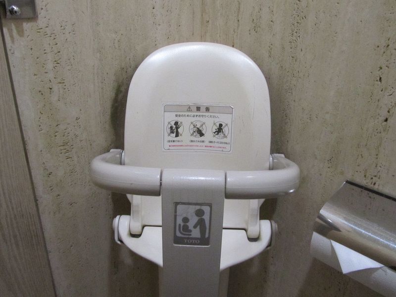 A baby seat in the toilet stall