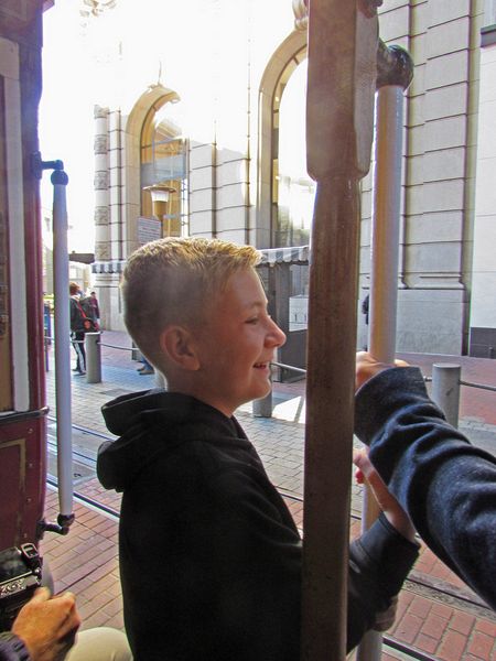 Nicholas stands on the outside of the cable car