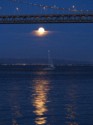 The moon reflects on the water as a boat sails by